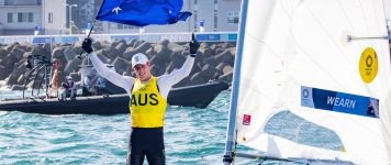 Matt Jerwood holding Australian Flag standing in laser at 2021 Toyko Olympics